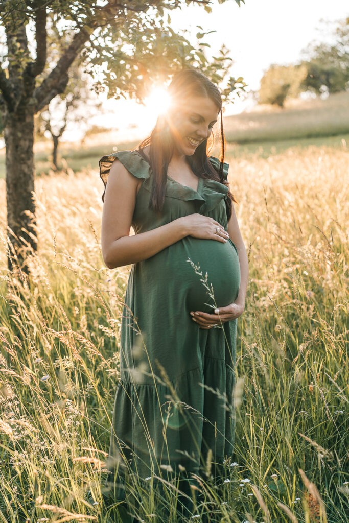 Das Foto ist bei einem Schwangerschaftsshooting beim in der Natur in Lörrach bei Sonnenuntergang entstanden - Selina Denz, deine Babybauchfotografin