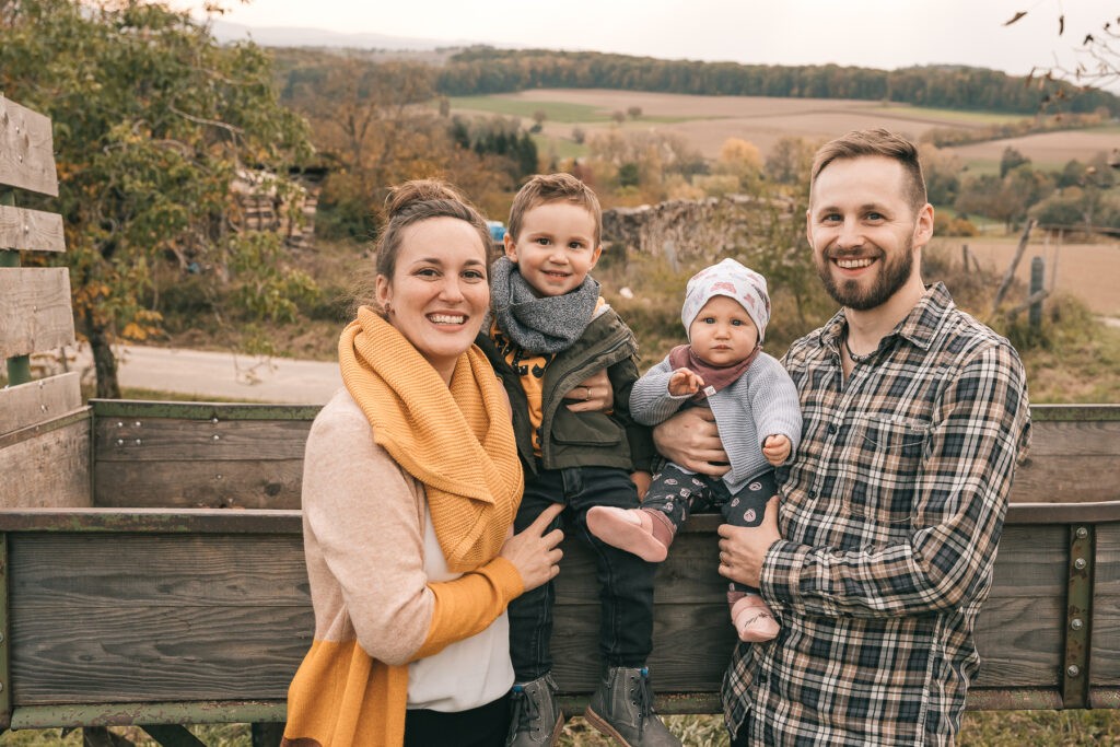 Mama, Papa, Sohn und Tochter beim Fotoshooting auf einem Traktor auf einem Feld in Kandern nahe Freiburg