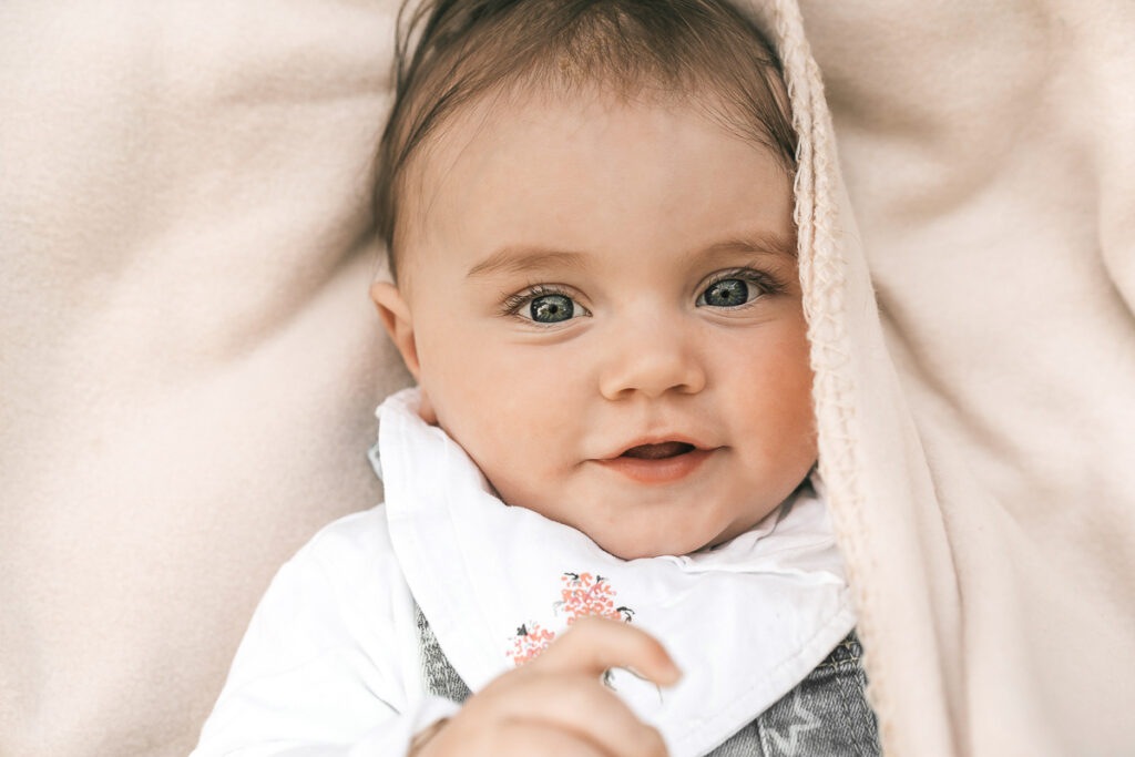Ein kleines Mädchen bei einem Fotoshooting auf einer Decke beim Picknicken am Fluss in der Nähe von Weil am Rhein - Selina Denz, deine Familienfotografin