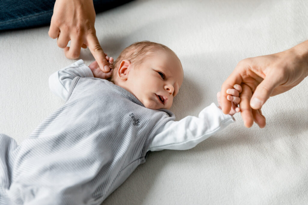 Auf dem Foto sieht man ein Neugeborenes und die Hände von Mama und Papa bei einem Homeshooting in Rheinfelden - Babyfotograf Selina Denz