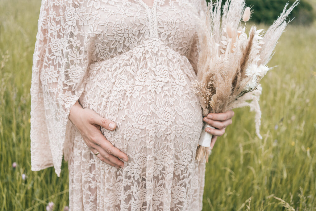 Detailbild eines Babybauchs mit Trockenblumen